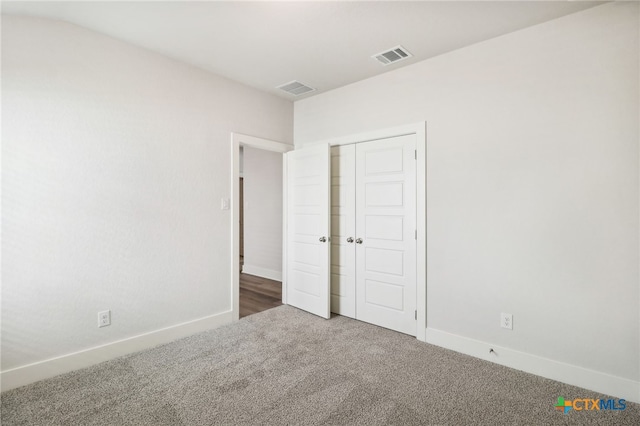 unfurnished bedroom with dark carpet and a closet