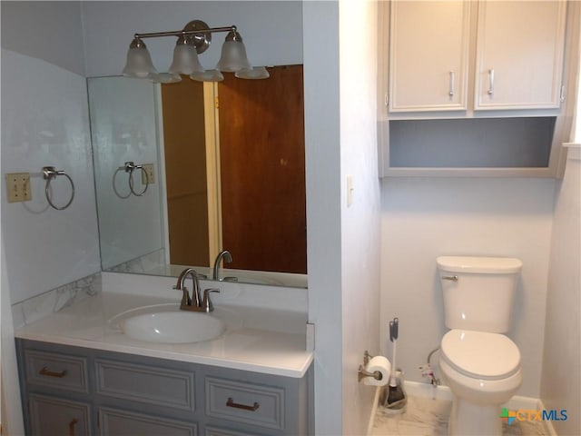 bathroom featuring toilet, baseboards, and vanity