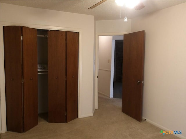 unfurnished bedroom with a closet, light colored carpet, ceiling fan, and baseboards