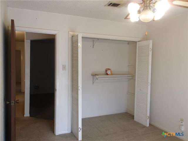 unfurnished bedroom featuring carpet, a closet, visible vents, a ceiling fan, and a textured ceiling