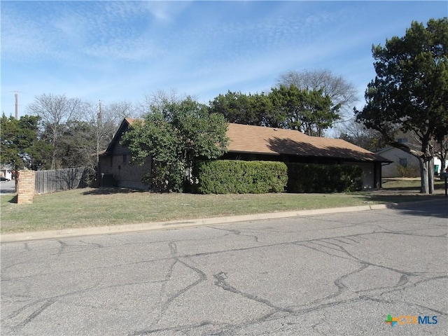 view of home's exterior with a lawn and fence