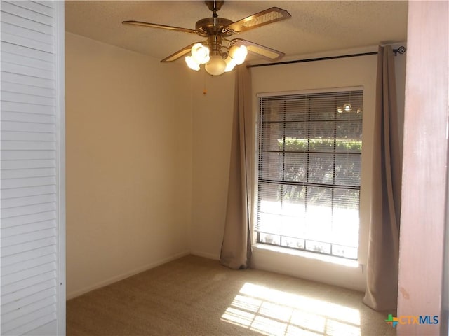 carpeted spare room featuring a ceiling fan, a textured ceiling, and baseboards