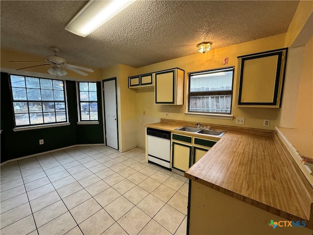 kitchen featuring a textured ceiling, white dishwasher, light tile patterned flooring, a sink, and a ceiling fan