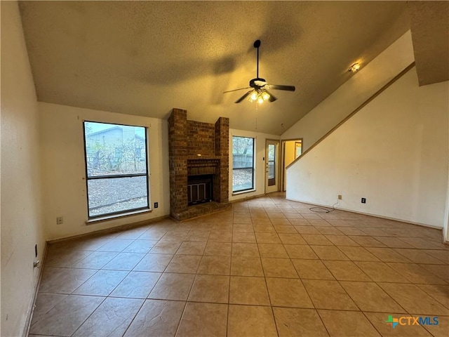 unfurnished living room featuring ceiling fan, light tile patterned floors, a textured ceiling, a fireplace, and vaulted ceiling