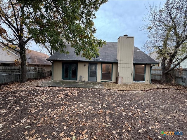 rear view of property with french doors, fence, a chimney, and a patio