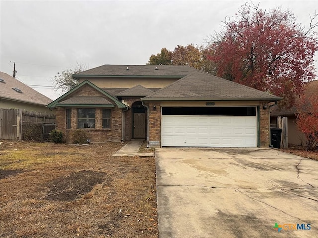 view of front of home with brick siding, fence, driveway, and an attached garage