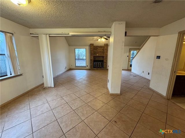 unfurnished living room featuring light tile patterned floors, ceiling fan, a textured ceiling, and a fireplace