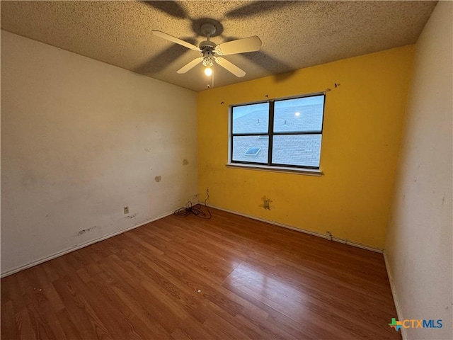 spare room featuring baseboards, a textured ceiling, a ceiling fan, and wood finished floors