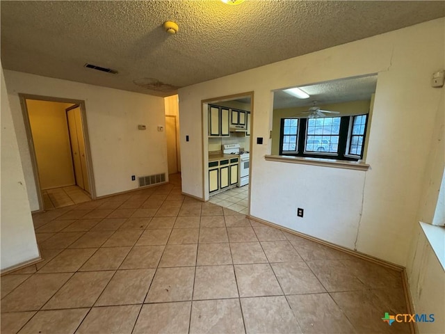 spare room with a ceiling fan, visible vents, a textured ceiling, and light tile patterned flooring