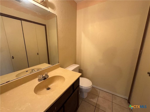 bathroom with tile patterned flooring, a textured wall, vanity, and toilet