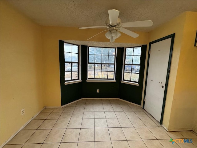 spare room with light tile patterned flooring, ceiling fan, and a textured ceiling