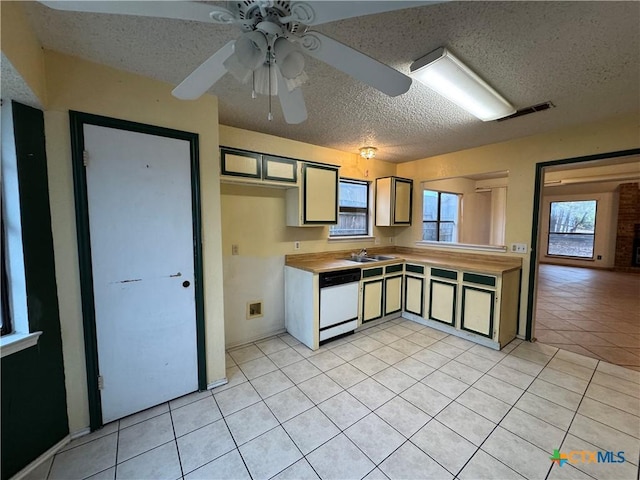 kitchen featuring light tile patterned floors, visible vents, dishwasher, a textured ceiling, and a sink