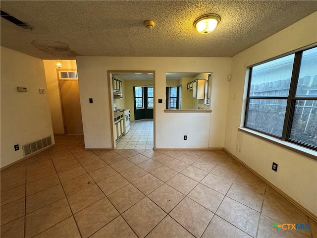 spare room with light tile patterned floors, visible vents, and a textured ceiling