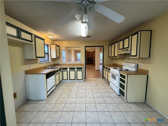 kitchen featuring light tile patterned floors, ceiling fan, a textured ceiling, under cabinet range hood, and white appliances