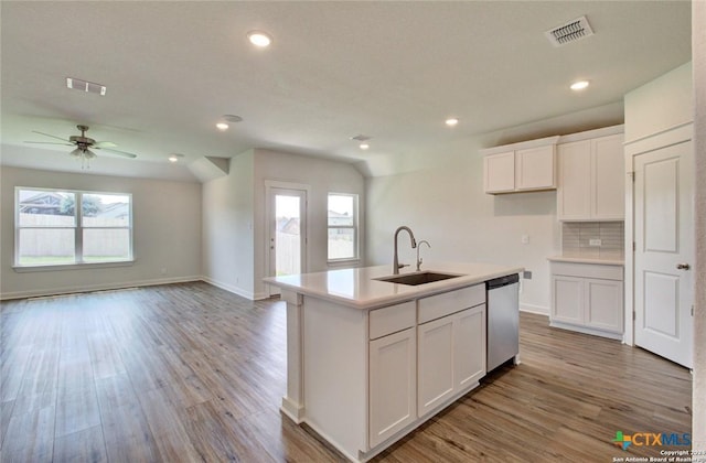 kitchen with white cabinets, visible vents, a sink, light wood-style floors, and stainless steel dishwasher