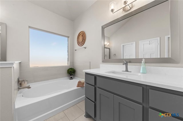 bathroom featuring tile patterned flooring, a bath, vanity, and vaulted ceiling