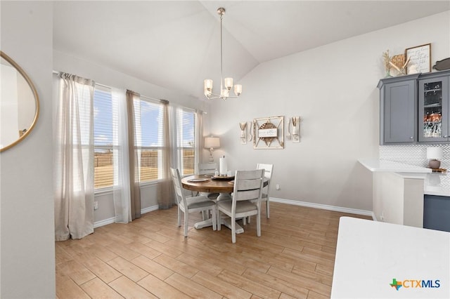 dining space with an inviting chandelier, light hardwood / wood-style floors, and vaulted ceiling