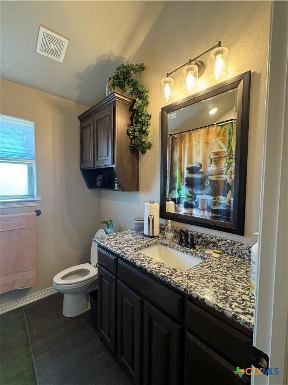 bathroom with toilet, vanity, visible vents, and baseboards