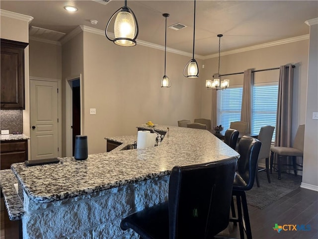 kitchen with dark wood-type flooring, a kitchen bar, visible vents, and crown molding