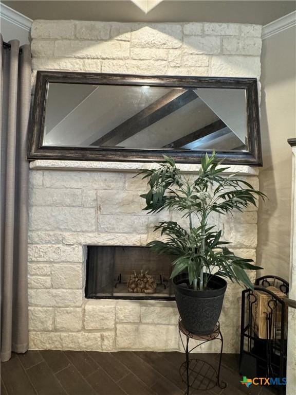 interior details with wood tiled floor, crown molding, and a stone fireplace