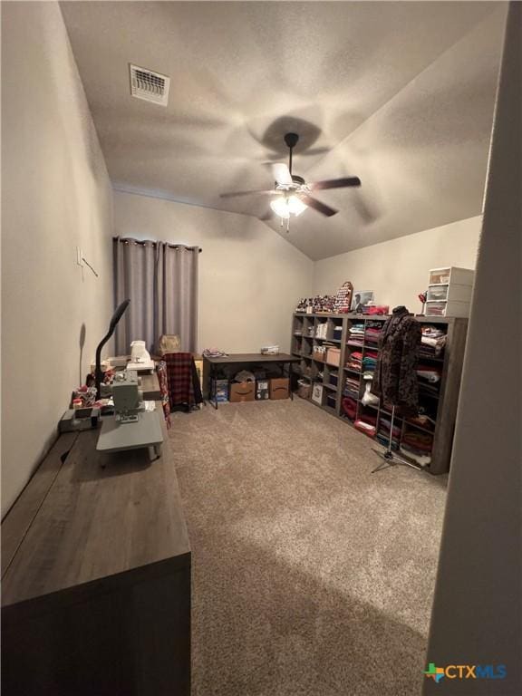 carpeted office featuring visible vents, vaulted ceiling, and a ceiling fan