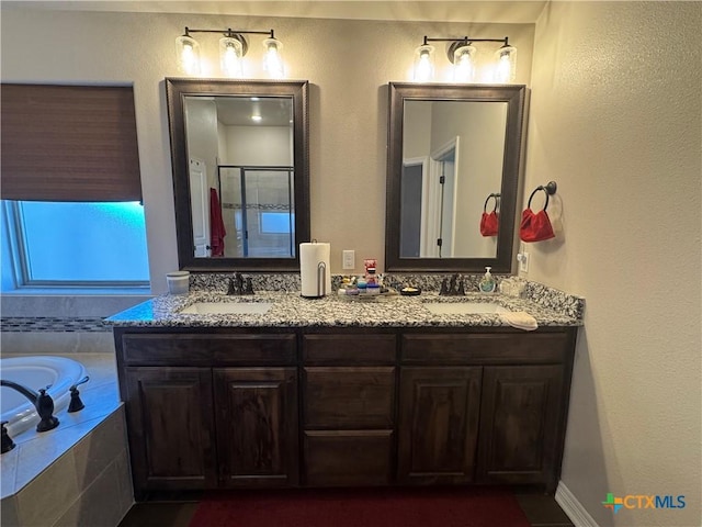 bathroom with a garden tub, a sink, a shower stall, and double vanity