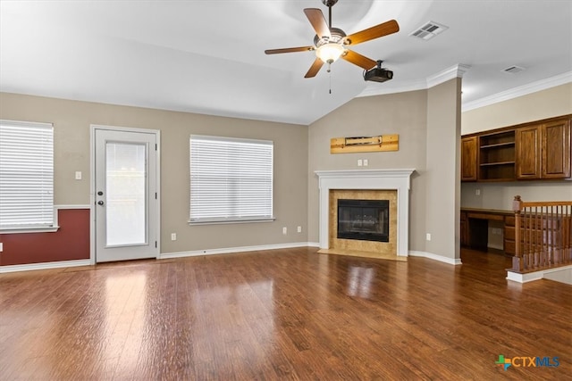 unfurnished living room with crown molding, a healthy amount of sunlight, dark hardwood / wood-style floors, and vaulted ceiling