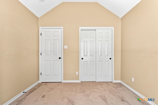 unfurnished bedroom featuring light colored carpet and vaulted ceiling