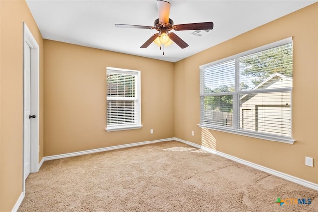 carpeted empty room with a wealth of natural light and ceiling fan