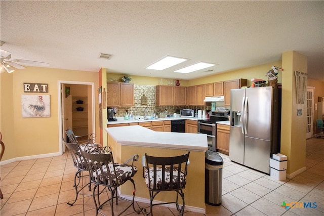 kitchen featuring tasteful backsplash, a textured ceiling, light tile patterned flooring, and stainless steel appliances