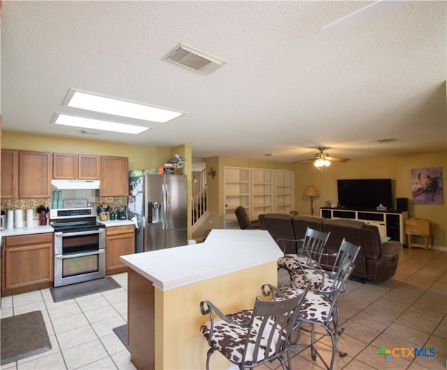 kitchen featuring appliances with stainless steel finishes, tasteful backsplash, ceiling fan, a textured ceiling, and light tile patterned floors