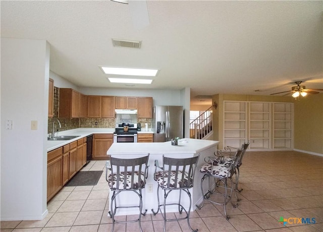 797 Killarney Rd, Floresville, TX 78114 - kitchen with under cabinet range hood, appliances with stainless steel finishes, a sink, and light tile patterned floors