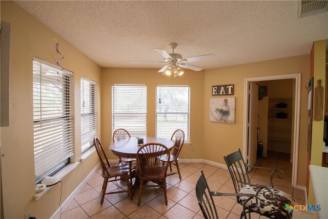 tiled dining space featuring a textured ceiling and ceiling fan