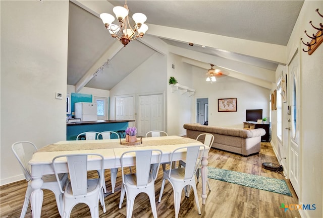 dining area with ceiling fan with notable chandelier, vaulted ceiling with beams, baseboards, and wood finished floors