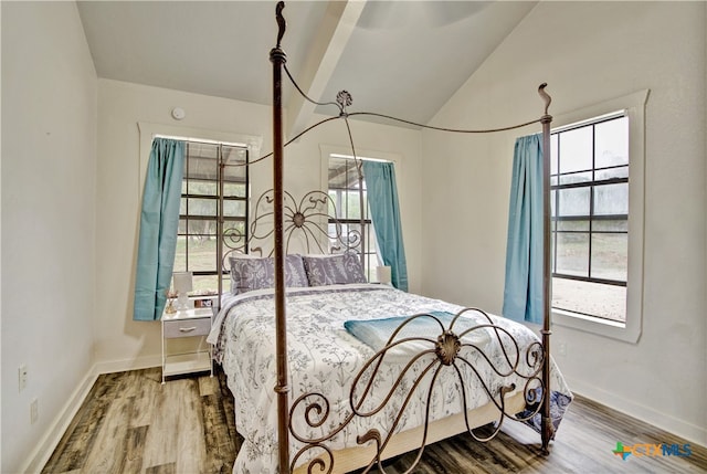 bedroom with vaulted ceiling, baseboards, and wood finished floors