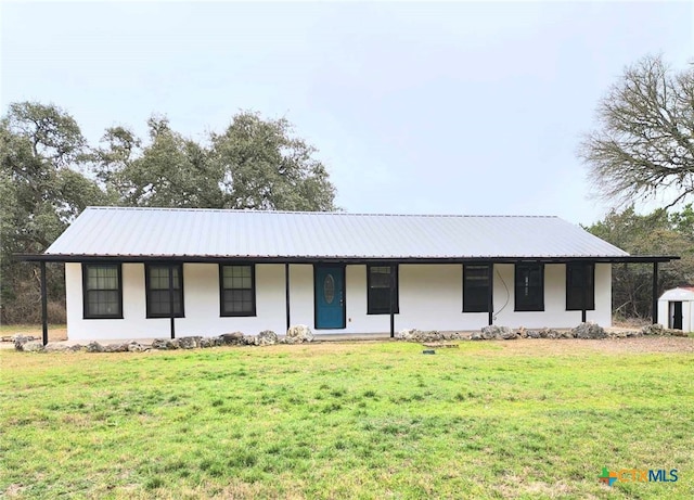 view of front of property featuring metal roof, a front lawn, and stucco siding