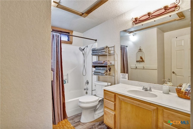 full bath featuring a textured wall, toilet, wood finished floors, vanity, and shower / tub combo with curtain