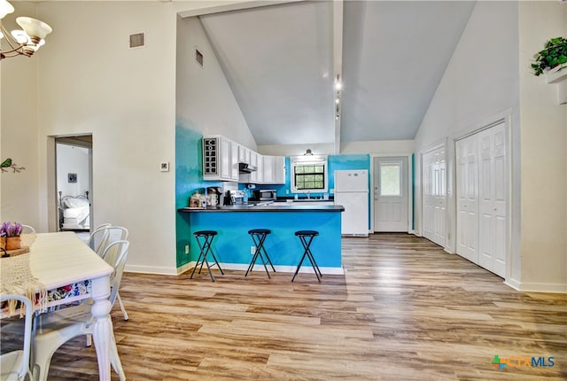 kitchen featuring visible vents, a breakfast bar, freestanding refrigerator, a peninsula, and light wood-type flooring