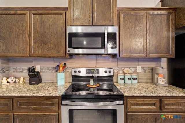 6407 Serpentine Dr, Killeen, TX 76542 - kitchen featuring appliances with stainless steel finishes, decorative backsplash, light stone countertops, and dark brown cabinets