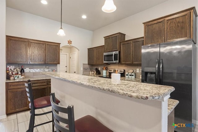 6407 Serpentine Dr, Killeen, TX 76542 - kitchen featuring stainless steel appliances, arched walkways, dark brown cabinets, light stone counters, and recessed lighting