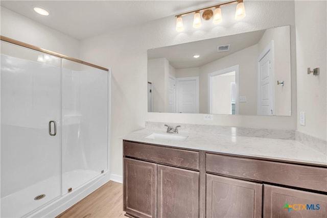 bathroom featuring vanity, hardwood / wood-style floors, and a shower with door