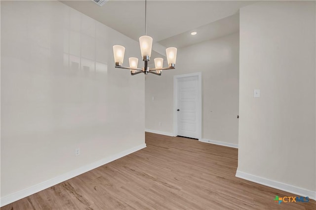 empty room featuring wood-type flooring and a chandelier