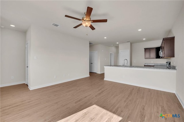 unfurnished living room featuring sink, ceiling fan, and light hardwood / wood-style flooring