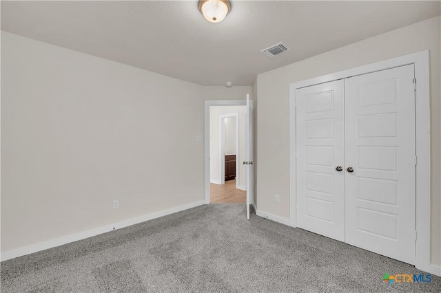 unfurnished bedroom featuring light carpet and a closet