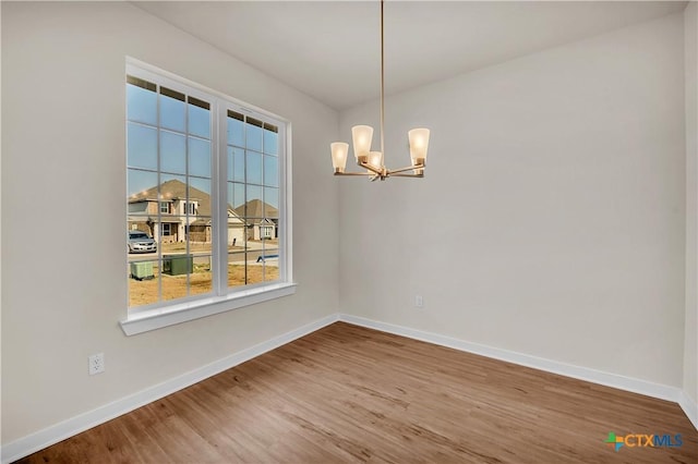 unfurnished room featuring an inviting chandelier and hardwood / wood-style floors