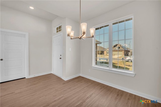 unfurnished dining area with hardwood / wood-style floors and a chandelier