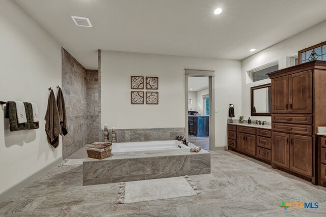 bathroom featuring vanity and tiled tub