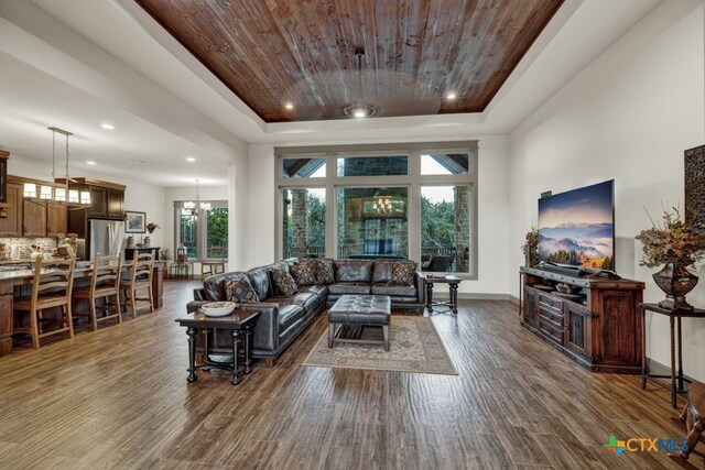 living room featuring a raised ceiling, dark hardwood / wood-style flooring, wood ceiling, and an inviting chandelier