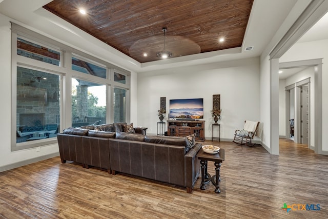 living room featuring a raised ceiling, hardwood / wood-style floors, and wooden ceiling