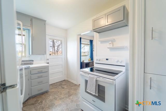 1710 S 15th St, Temple, TX 76504 - kitchen with white electric range, gray cabinetry, healthy amount of natural light, and light countertops